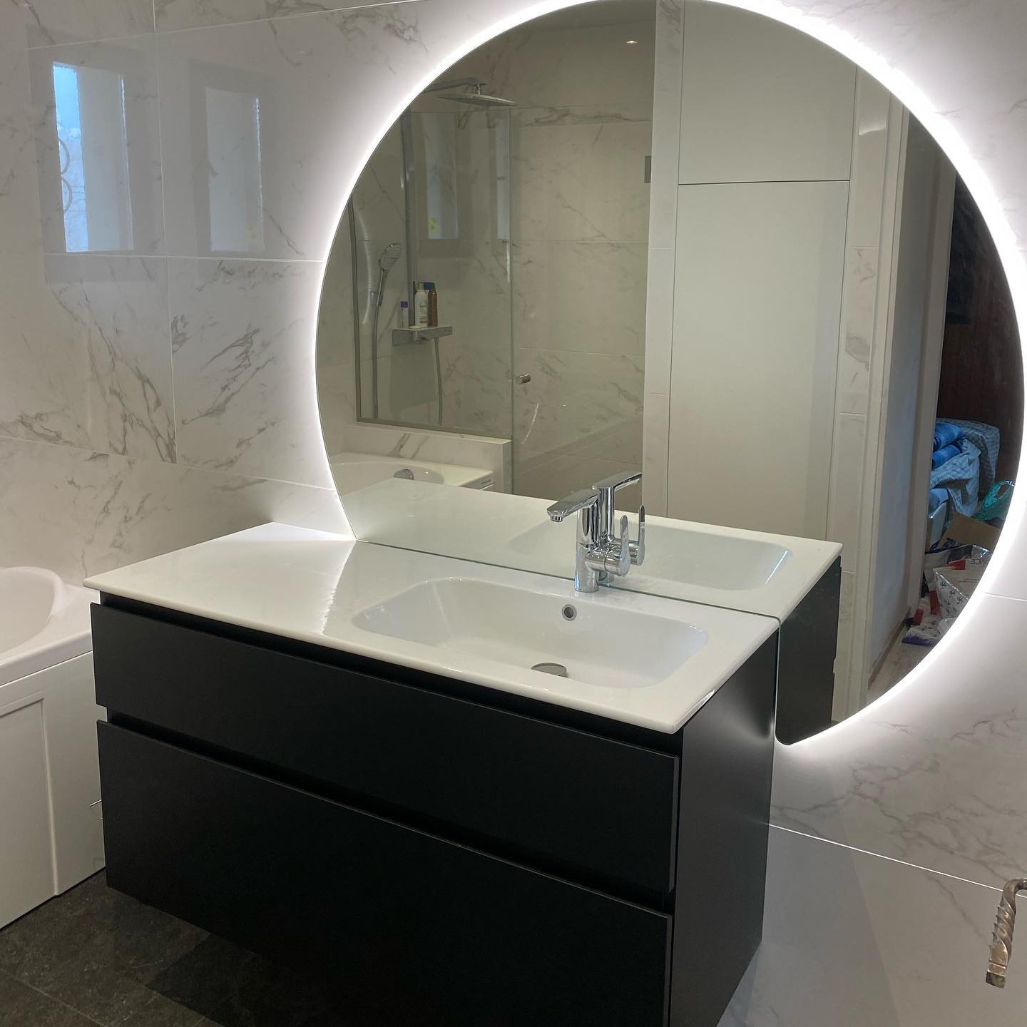 Photo d'un lavabo avec miroir rond lumineux dans une salle de bain en marbre blanc