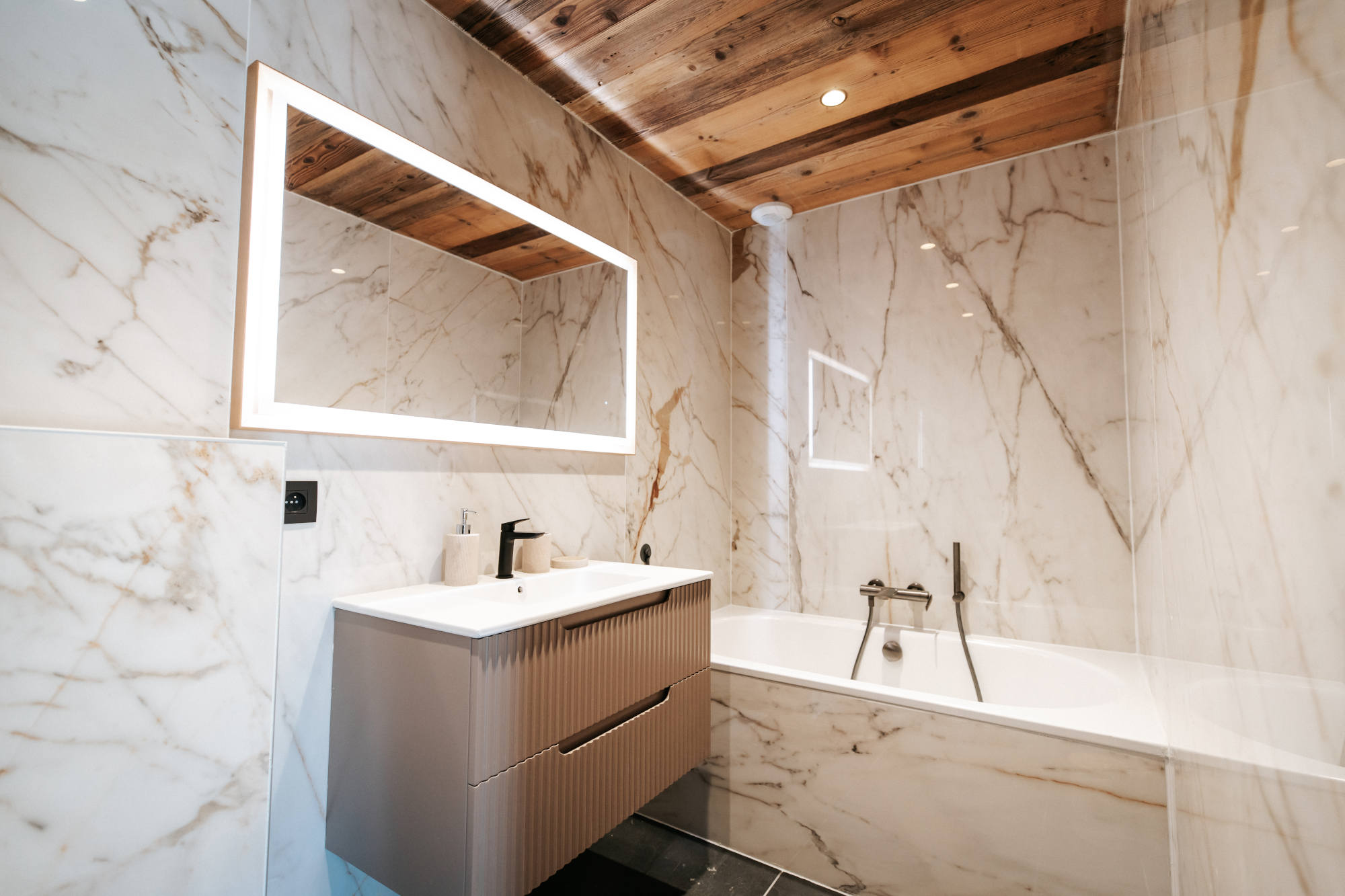Photo de l'aménagement d'une douche en marbre blanc avec un plafond en bois par la société Mont-Blanc Renov'all à Sallanches